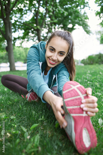 Cuadro en lienzo Portrait of young and sporty woman in sportswear doing yoga or Stretching exercises outside at the park on green field on cloudy day, Dnipro, Ukraine