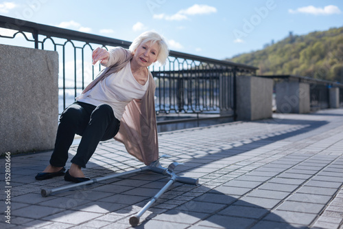 Retired lady getting up from the ground outdoors