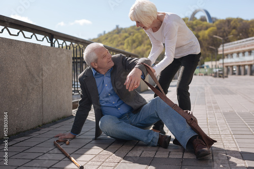 Merry pensioner sitting on the street and receiving help photo