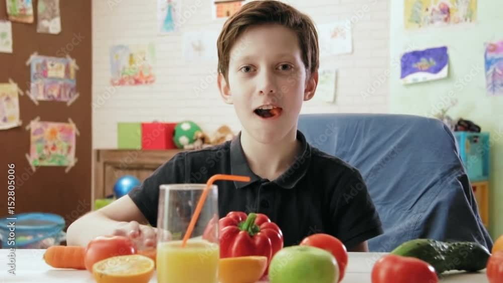 Cute little boy eating carrot and looking at the camera Cute little boy eating carrot and looking at the camera