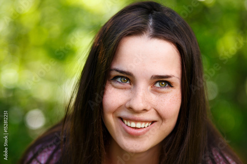 Young beautiful freckled green-eyed woman face with healthy skin and wide smile  close-up portrait