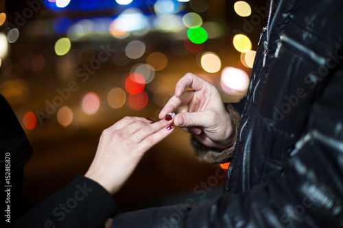 A closeup of a man putting an engagement ring