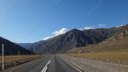 landscape of road in wild field with mountains at horizon