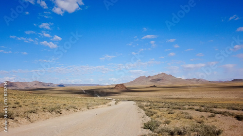 landscape of outdoor road in wild field with mountains at horizon