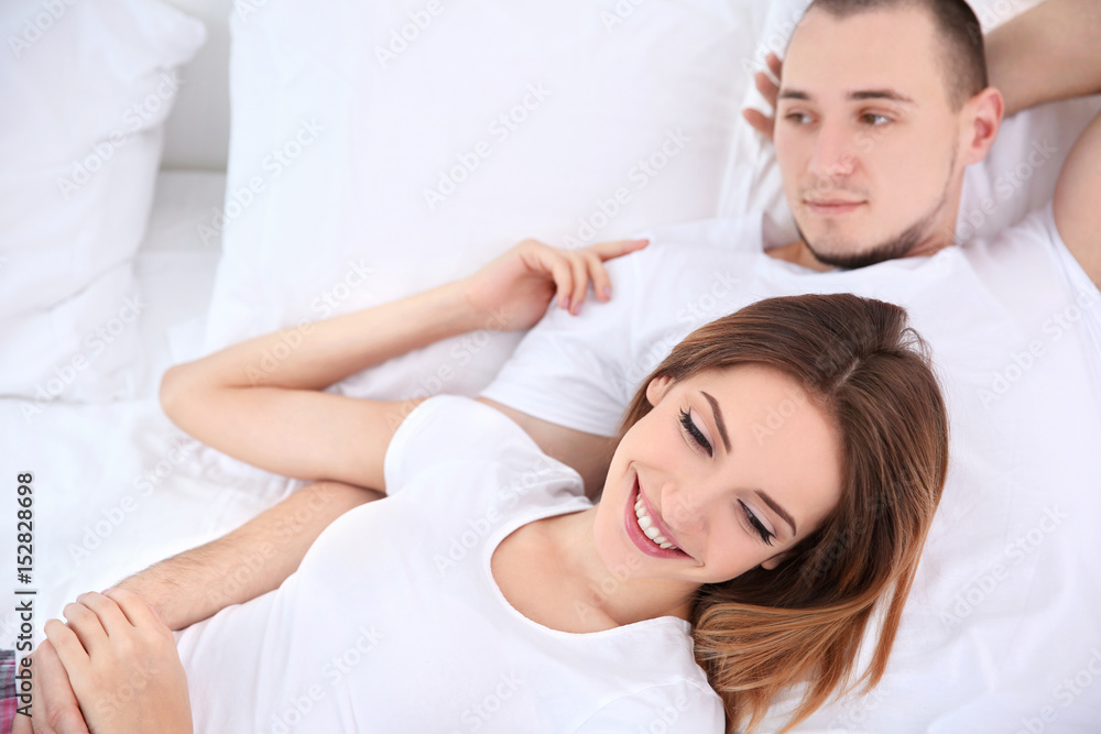 Young couple lying together in bed Young couple lying together in bed
