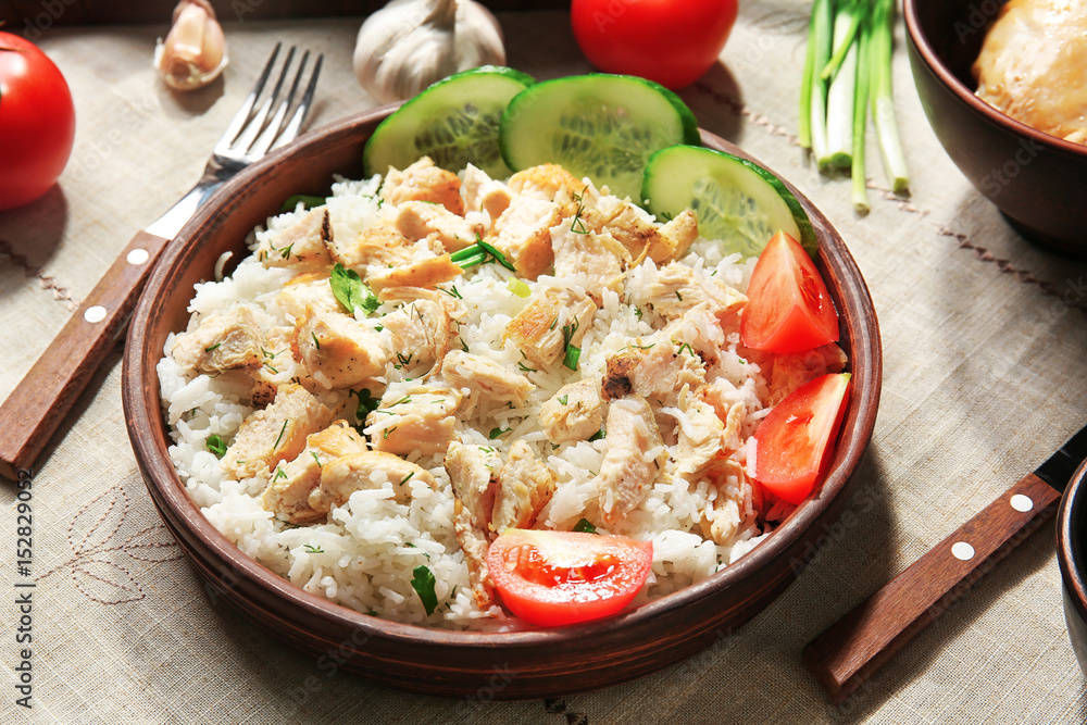 Delicious rice with chicken and vegetables in bowl on table Delicious rice with chicken and vegetables in bowl on table