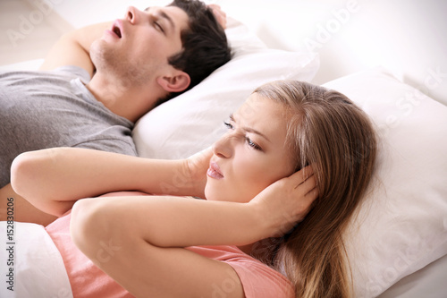 Young irritated woman lying in bed with snoring husband at home © Africa Studio