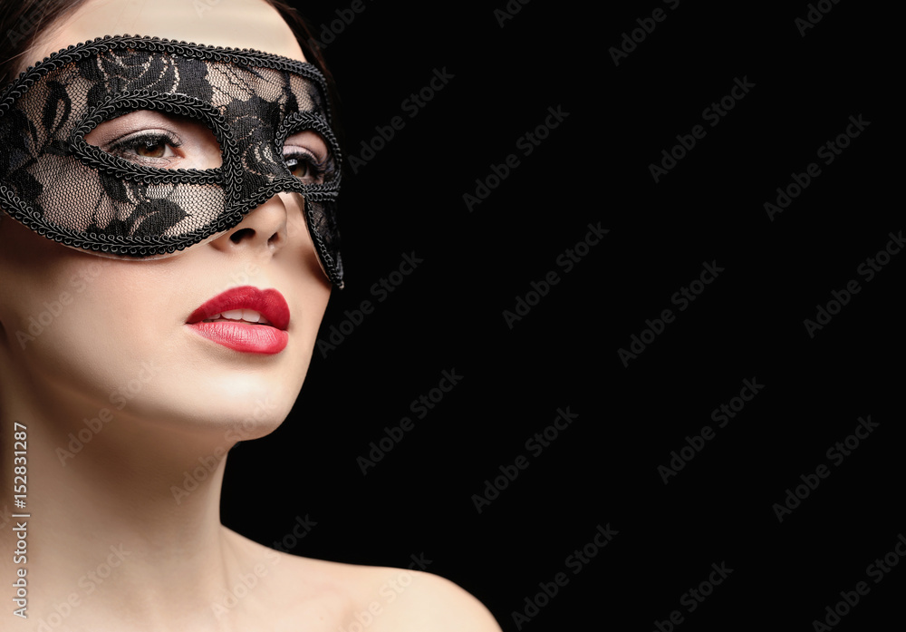 Beautiful young woman in mask on black background