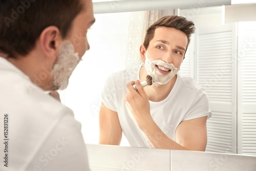 Handsome man shaving in bat...