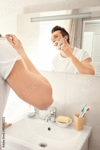 Handsome man shaving in bat...