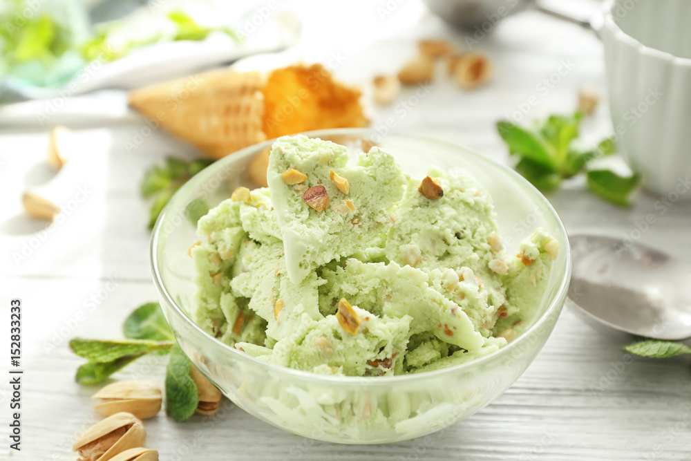 Glass bowl with delicious pistachio ice cream on white wooden table