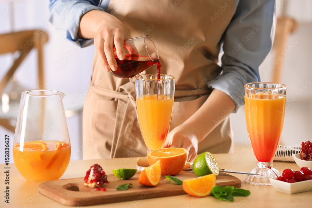 Woman preparing Tequila Sunrise cocktail in kitchen Woman preparing Tequila Sunrise cocktail in kitchen