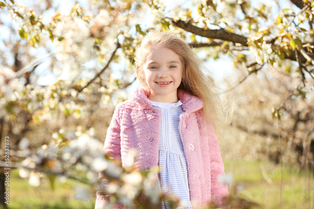 Little smiling girl near blooming tree in spring garden Little smiling girl near blooming tree in spring garden