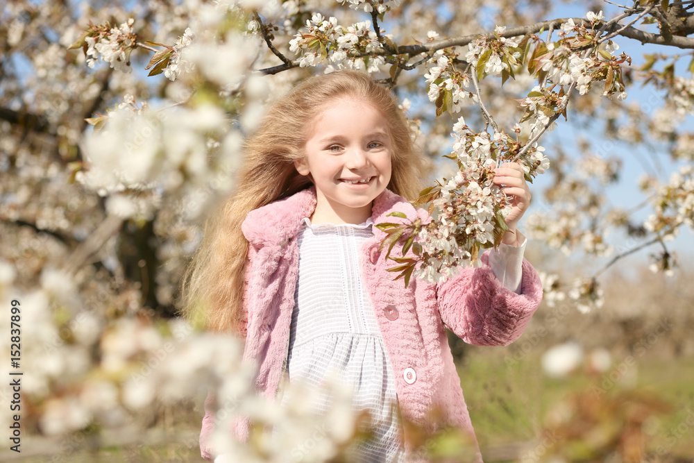 Little smiling girl near blooming tree in spring garden Little smiling girl near blooming tree in spring garden