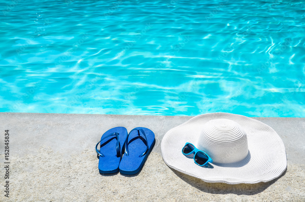 Fototapeta premium Summer background with hat, flip flops and sunglasses near the pool