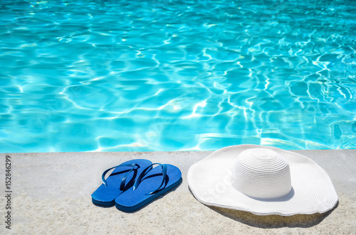 Summer background with hat, flip flops and sunglasses near the pool