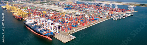 Aerial view of cargo ships loading containers at seaport.