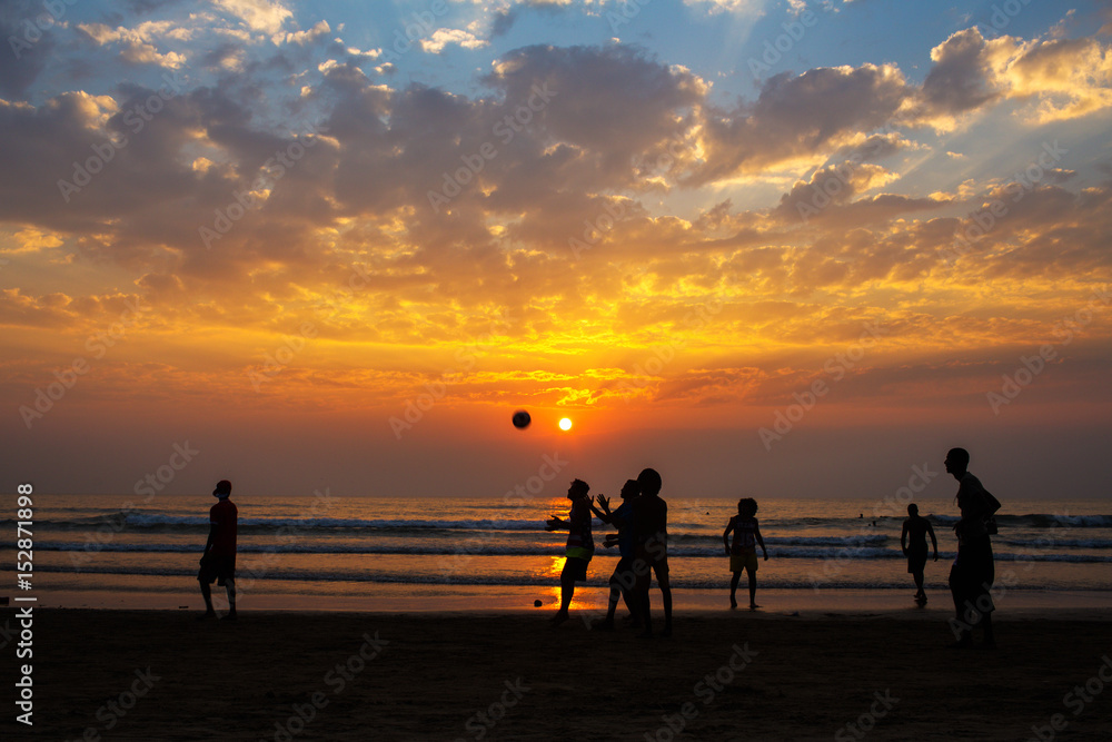  Group of people play football on the sand beach at the sunset