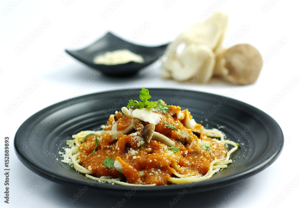 Sauteed mushroom with tomatoes sauce and ramen noodle on black dish Sauteed mushroom with tomatoes sauce and ramen noodle on black dish