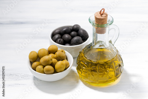 bottle with olive oil and bowls with olives, top view