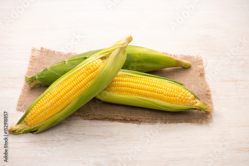 Sweet corns. Fresh corn on cobs on wooden table.