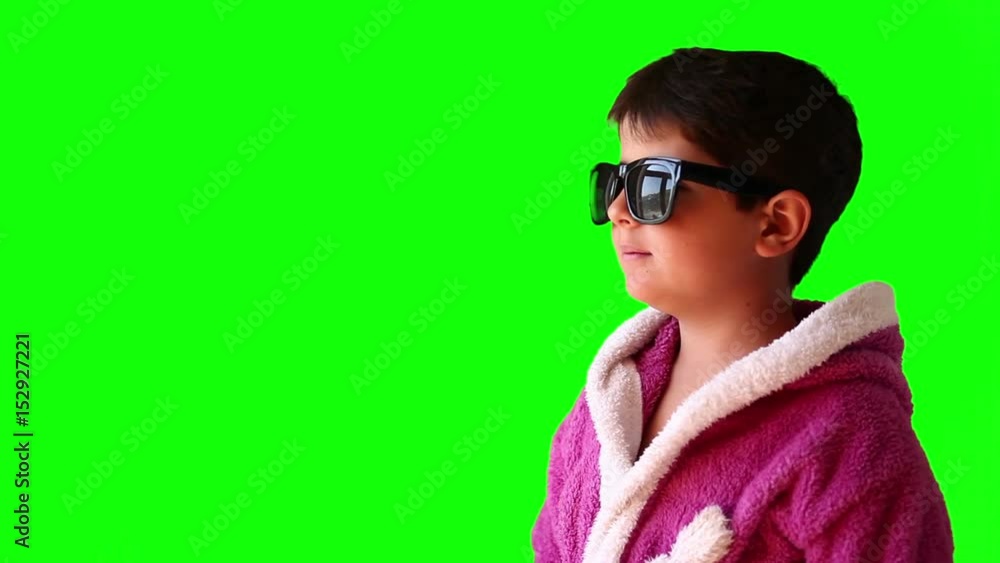 A boy in a bathrobe and sunglasses makes faces on green screen A boy in a bathrobe and sunglasses makes faces on green screen