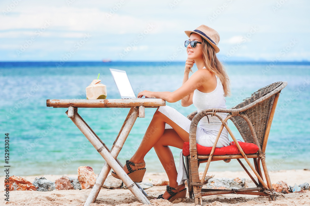 Young sexy woman using laptop on the beach. Freelance work