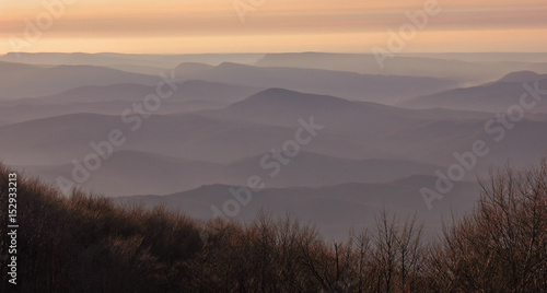 Silhouettes of mountains in fog to the horizon during sunset. Pattern with empty space for text