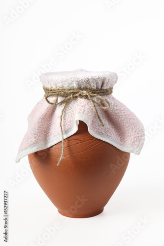 A ceramic jug covered with a cloth napkin. Isolated on a white background