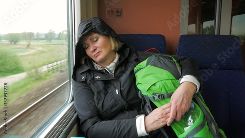 Tired woman rides on the train and sleeps against the window. photo