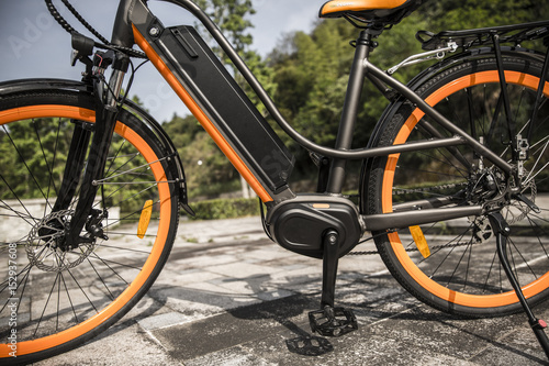 Electri bicycle ebike , orange and black with trees in background