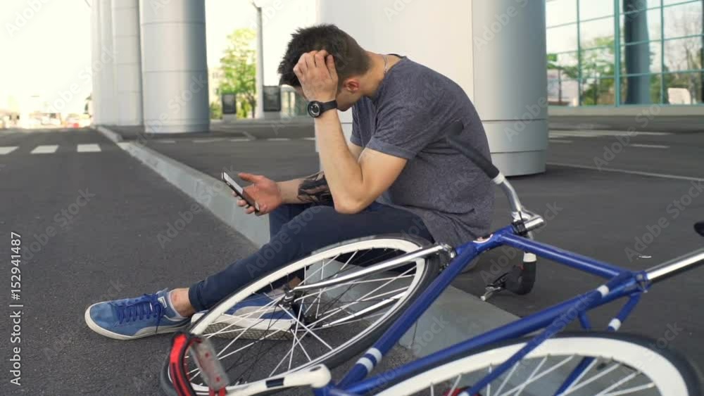 Man sitting on the border scrolling websites and fixes his hair slow motion Man sitting on the border scrolling websites and fixes his hair slow motion