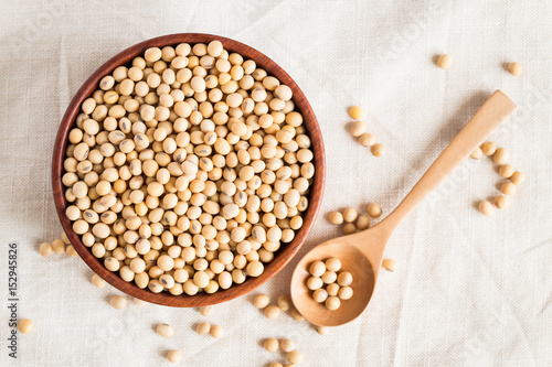 Soybeans in a wooden cup on a tablecloth Background, top view