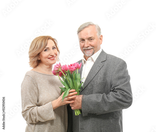 Happy senior couple with bouquet of flowers isolated on white © Africa Studio