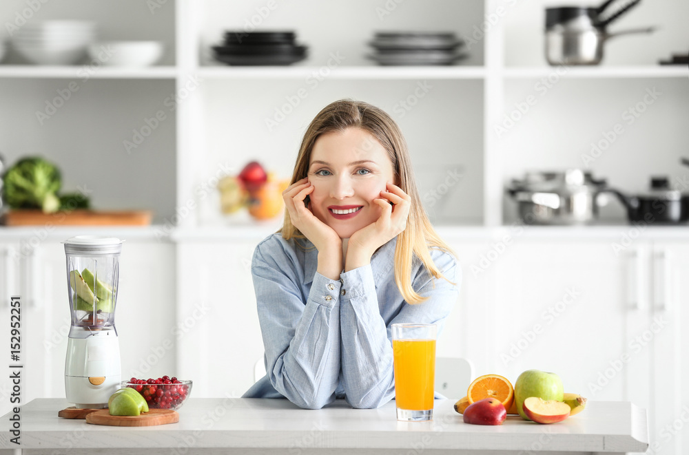 Beautiful woman with glass of fresh juice in kitchen