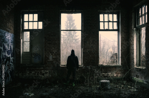 Lonely depressed man standing at dark abandoned factory.