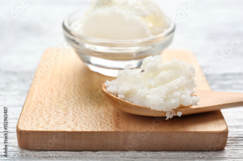 Shea butter in bowl and spoon on wooden board, close up