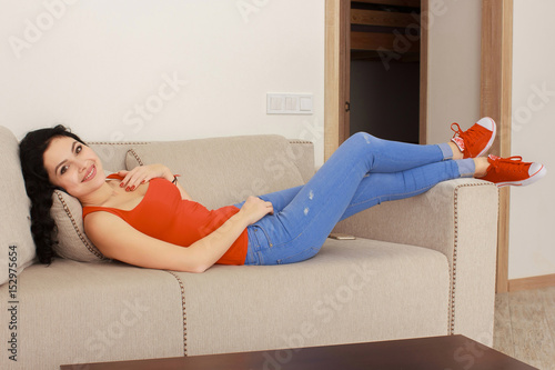 home and happiness concept - smiling young woman lying on sofa at home photo