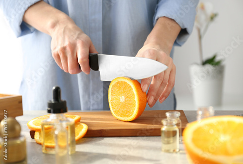 Woman cutting orange, closeup
