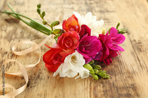 Bouquet of beautiful freesia flowers on wooden background, closeup