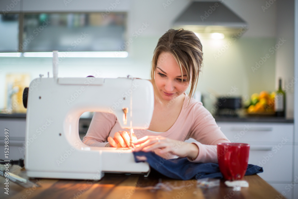 Beautiful young woman sewing clothes with sewing machine (color toned image; shallow DOF) Beautiful young woman sewing clothes with sewing machine (color toned image; shallow DOF)