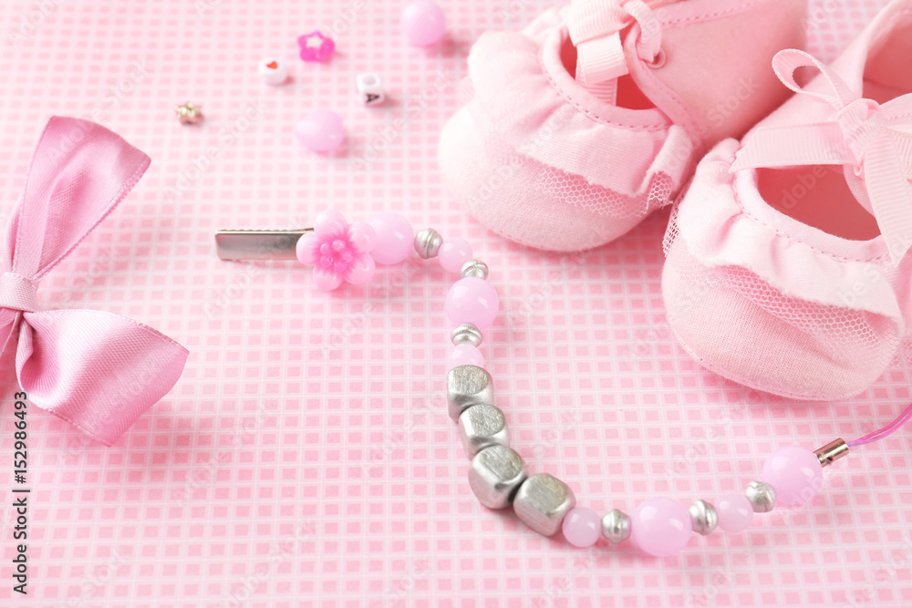 Composition with pacifier clip for baby, booties and bow knot on table Composition with pacifier clip for baby, booties and bow knot on table