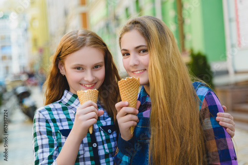 Portrait of two teenager girls standing together eating ice cream