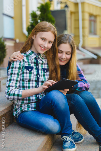 smiling teenage girls with tablet pc computer outdoors