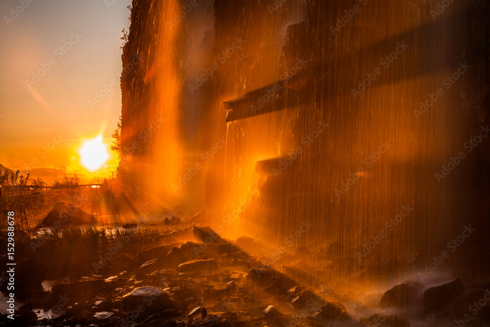 The sun illuminates the waterfall at sunset. Norway