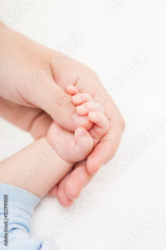 Mother holding newborn baby child little hand with small fingers