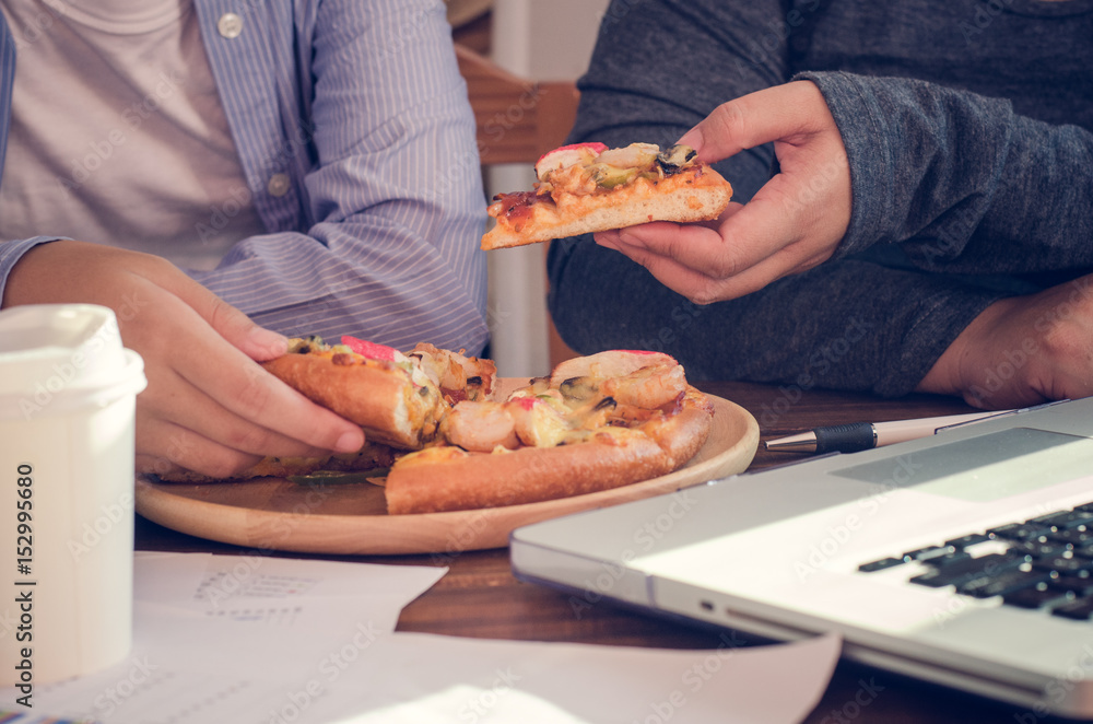 Business team is eating pizza at work while working