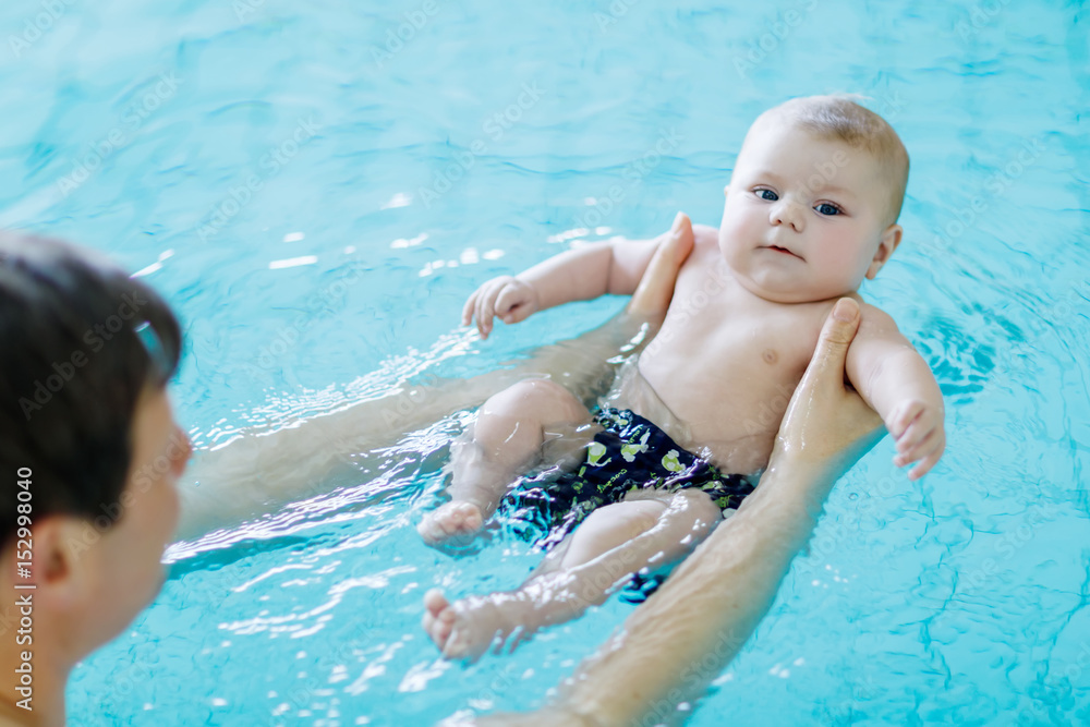 Happy middle-aged father swimming with cute adorable baby in swimming pool. Happy middle-aged father swimming with cute adorable baby in swimming pool.