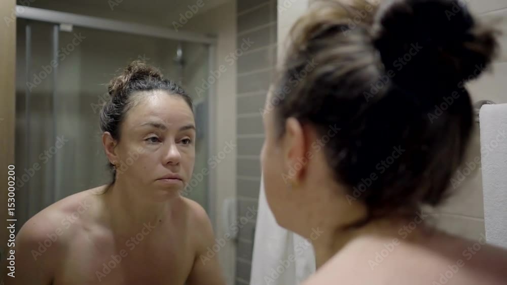 A middle-aged woman stands in the bathroom of the hotel and brings the eye makeup A middle-aged woman stands in the bathroom of the hotel and brings the eye makeup