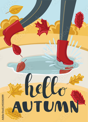 Girls or kids legs in rubber boots playing in the puddle. Falling leaves arround. Children jumping and splashing through the puddles in park in the Fall. Hello Autumn concept.